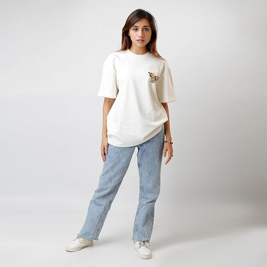 Person wearing a white t-shirt with a small design and light blue jeans on a plain background