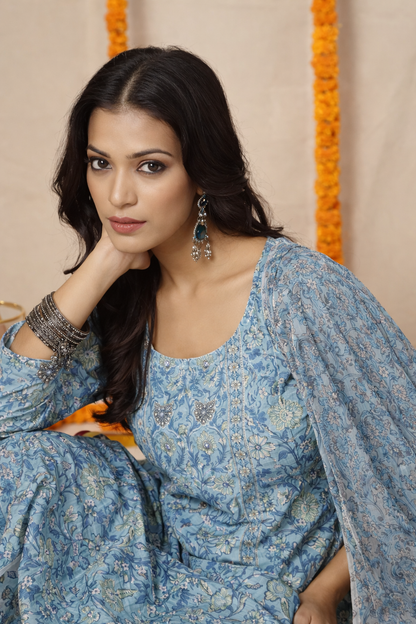 Woman wearing a blue floral dress against a beige background