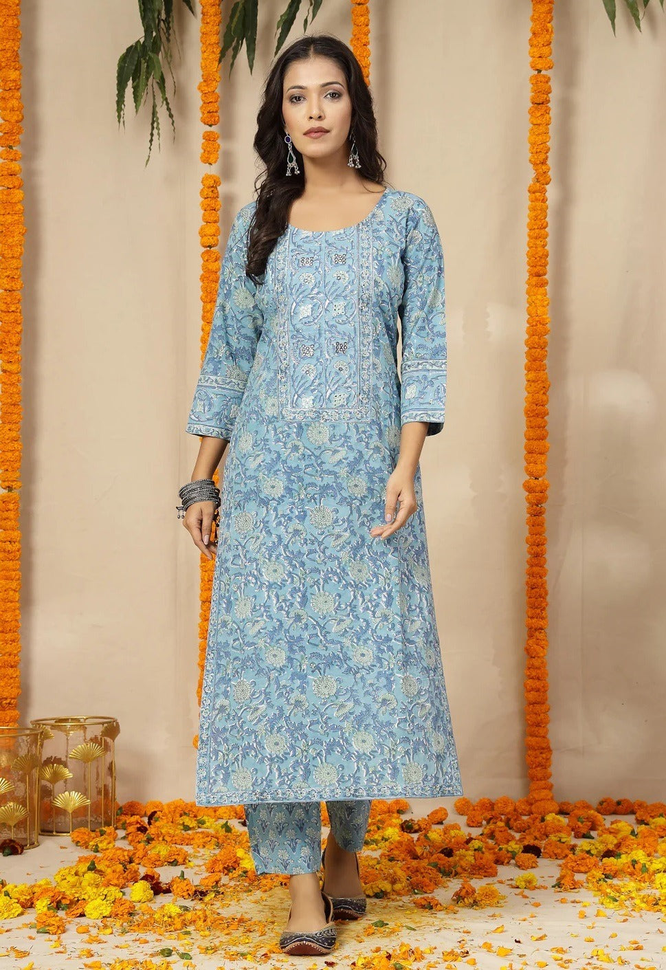 Woman wearing a blue floral kurta with a beige background and decorative elements.