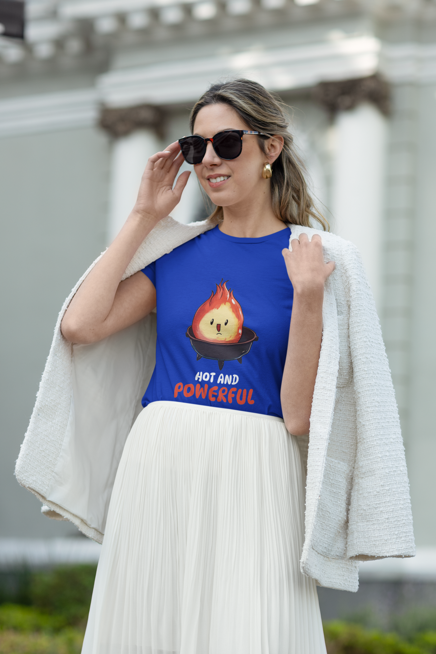 Woman wearing a blue t-shirt with a graphic design and text, standing outdoors.